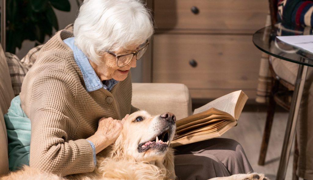 Client cuddling her dog and reading a book in her living room